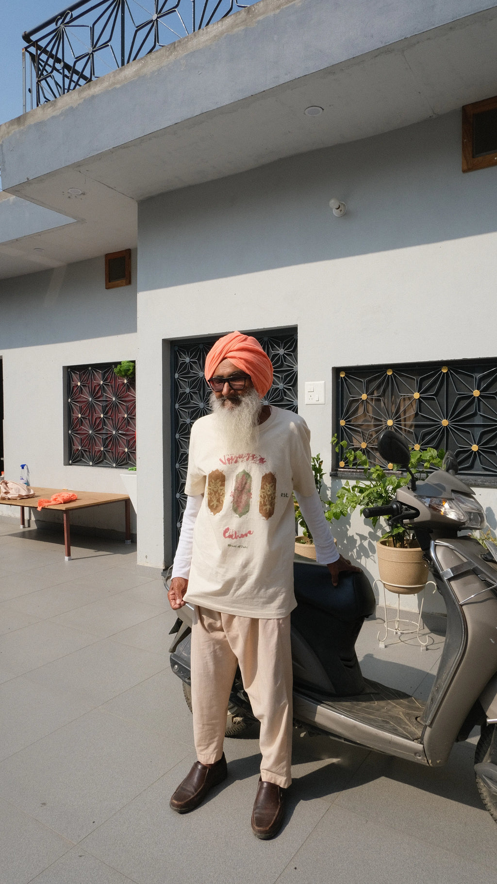 bapu standing in front of his scooter wearing a handprinted tshirt