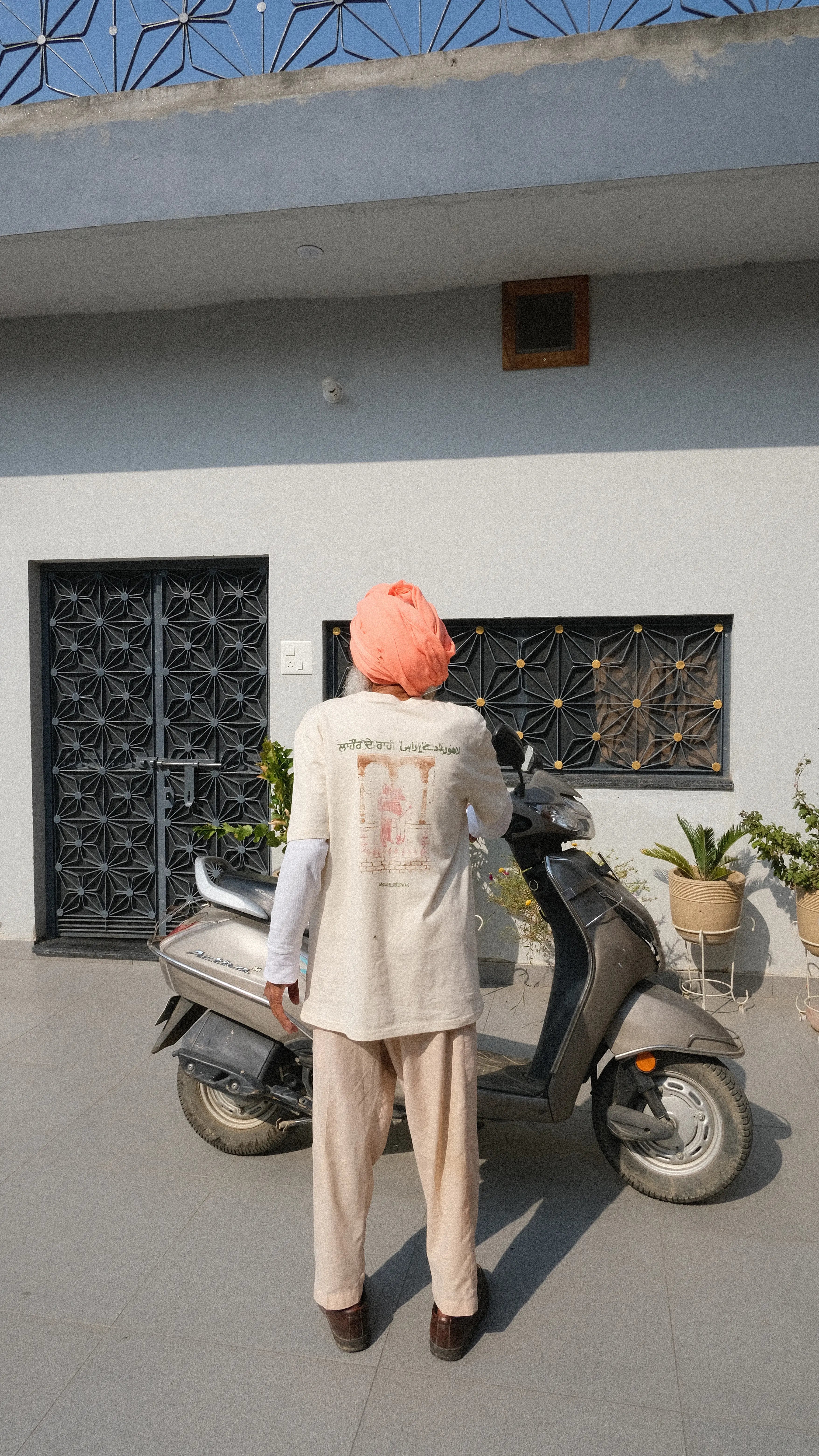 bapu standing in front of his scooter wearing a handprinted tshirt