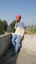 Singh wearing a Denim scarf on his shoulder standing on a concrete surface with a clear sky of Punjab in the background.
