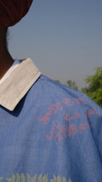 Singh wearing a Denim scarf on his shoulder standing on a concrete surface with a clear sky of Punjab in the background.