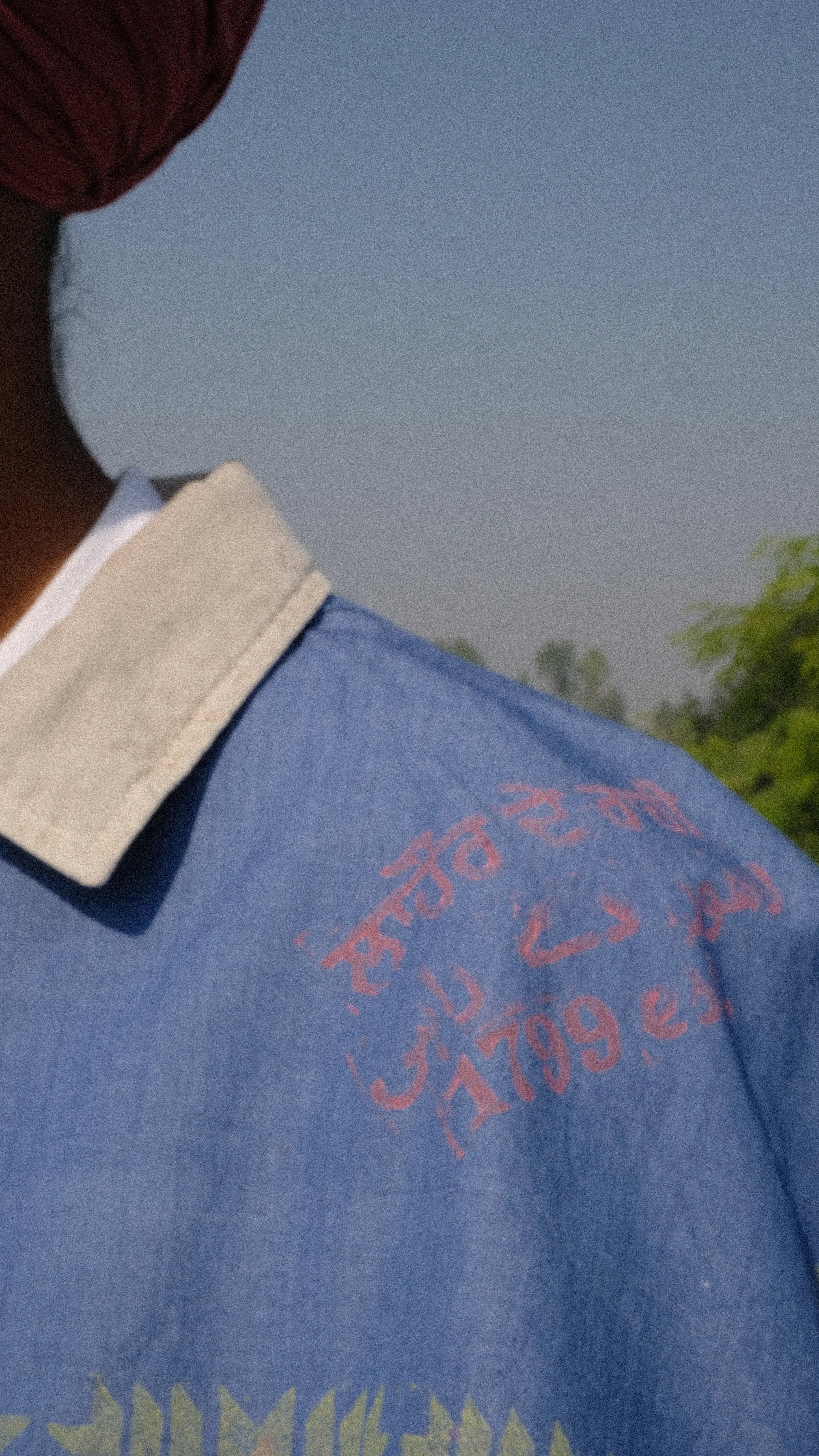 Singh wearing a Denim scarf on his shoulder standing on a concrete surface with a clear sky of Punjab in the background.